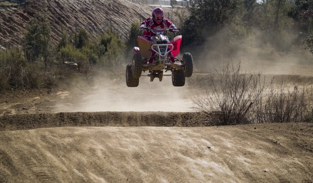 Adventurer wearing red helmet and suit jumping with quad