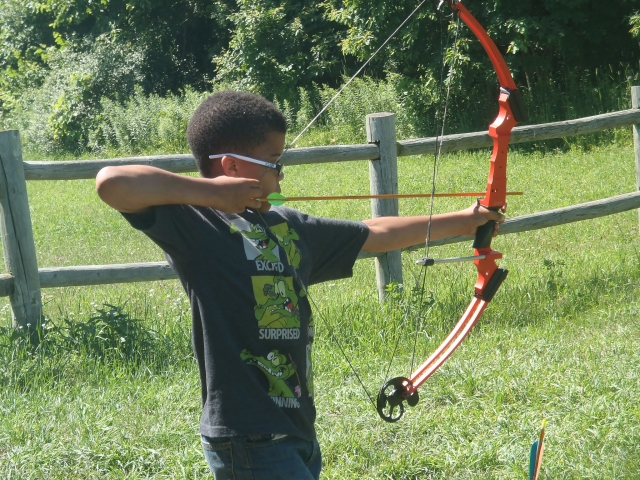Boy waring sunglasses doing archery