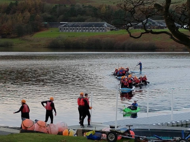 People wearing red buoyancy aids and black wetsuit rafting