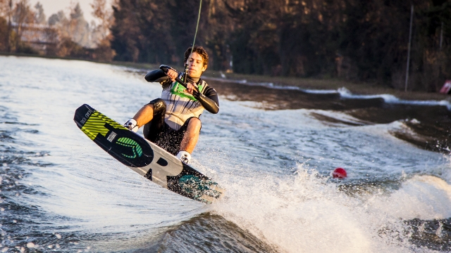 Boy wearing green and black wetsuit wakeboarding
