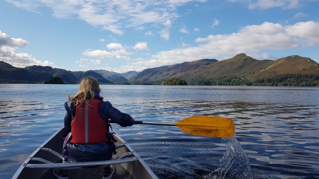  Fille portant des aides à la flottabilité rouges faisant du canoë et des montagnes devant elle 