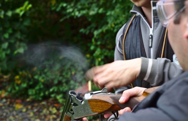  Dois homens carregando o rifle para fazer tiro de argila disparando 
