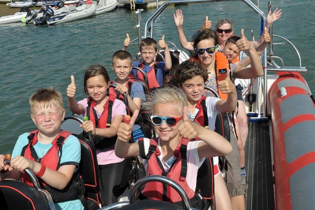 Kids wearing red buoyancy aids having fun during their boat trip