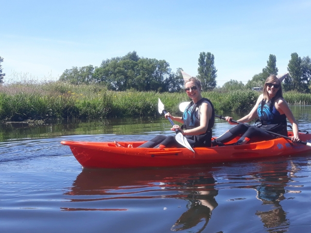  Dos niñas sonriendo y vistiendo gafas de sol en kayak en el puerto 