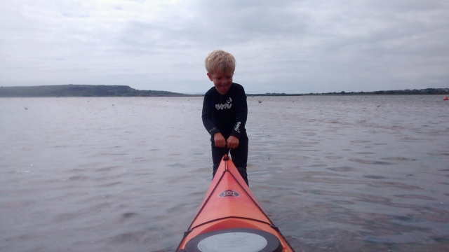  Jeune petit garçon tirant le kayak rouge vers la mer pour commencer sa session de kayak 