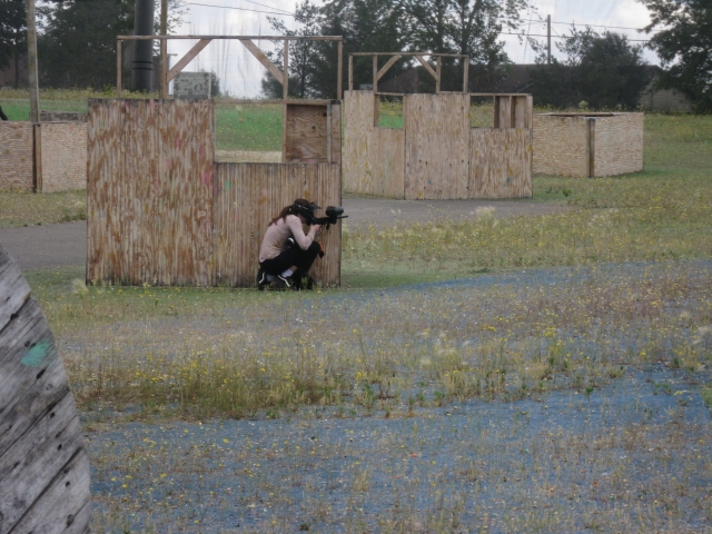 Femme se cachant en jouant au paintball