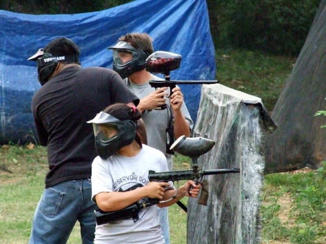 Trois personnes jouant au paintball avec équipement de sécurité sur