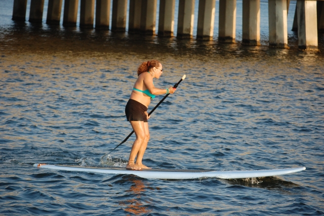 Woman in blue and black bikini paddleboarding