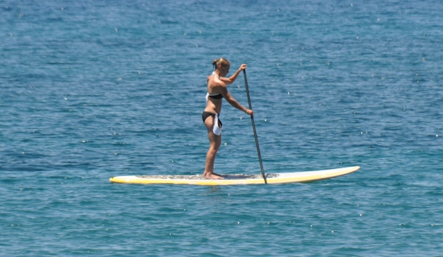 Woman in black and blue bikini paddleboarding