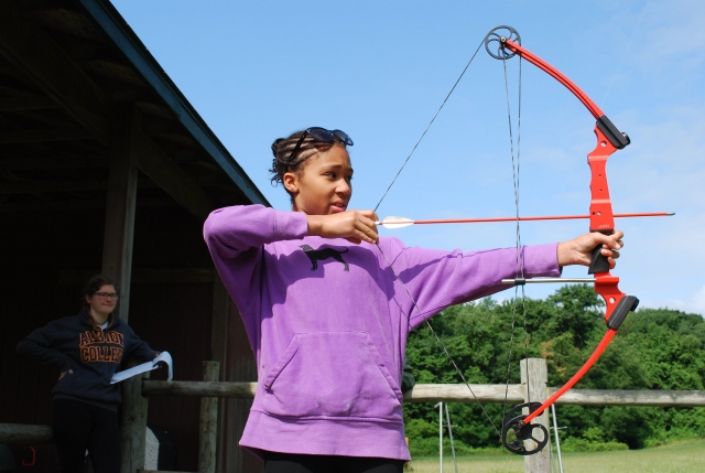  穿紫色毛衣的女孩练习射箭