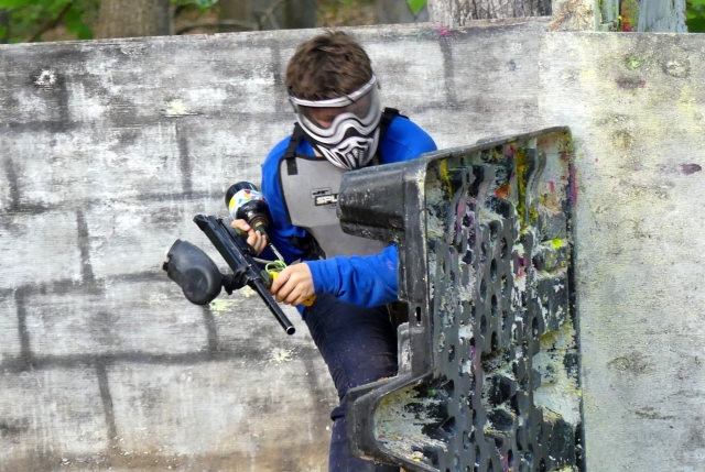  Garçon jouant au paintball en costume bleu et portant un masque gris 