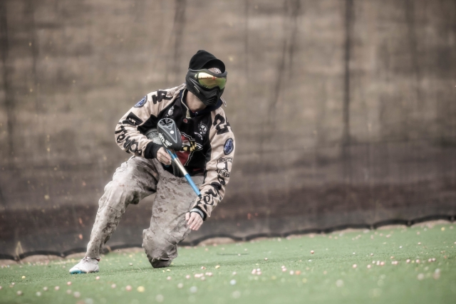  hombre en traje de camuflaje corriendo mientras realiza paintball 
