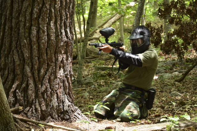  Uomo in ginocchio che gioca a paintball e indossa una tuta mimetica 