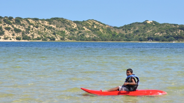  Junge auf rotem Kajak und mit blauen Schwimmhilfen beim Kajakfahren 