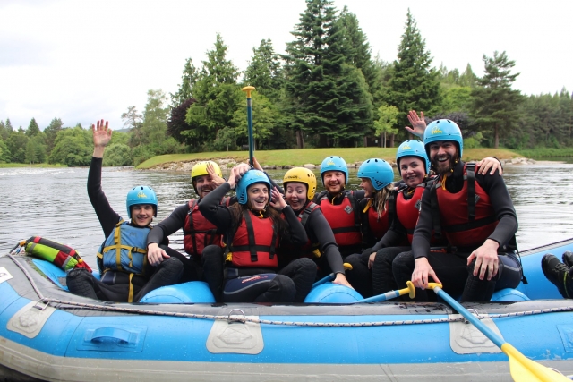  Freundinnen lächeln und tragen rote Schwimmhilfen und blaue Helme während ihrer Rafting-Session