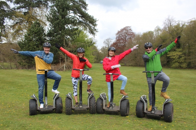 Friends wearing blak helmets and raising arms before doing segway
