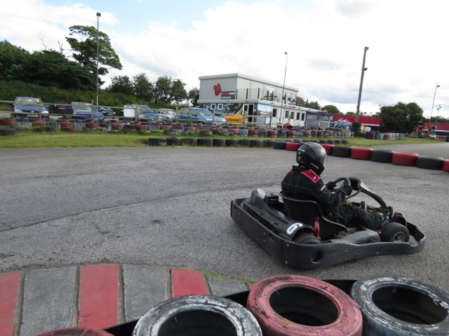 Driver in black driving suit karting