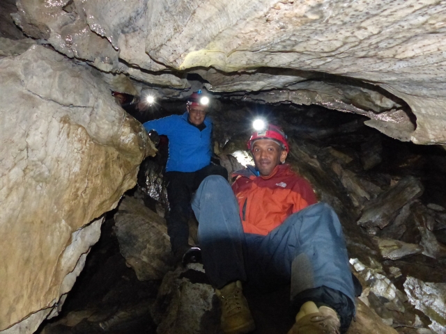 Man in orange jacket and woman in blue jacket caving