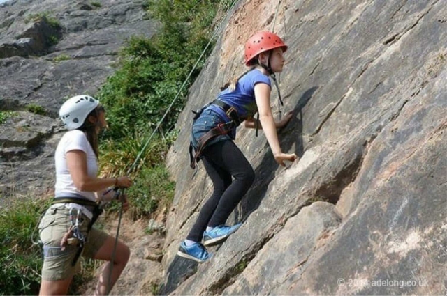  Fille portant un casque rouge pendant l'escalade avec sa mère, vêtue de blanc 