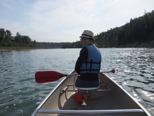 Woman wearing hat and blue buoyancy aids while canoeing