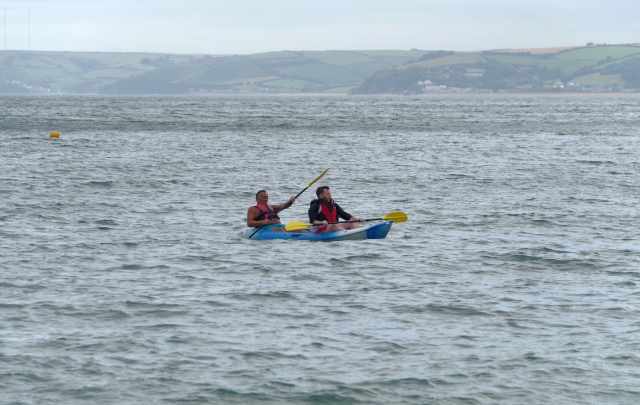 Men wearing red buoyancy aids and canoeing on the river