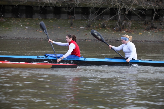 Two woman, one in red buoyany aids, and the other wearing blue jacket canoeing and having fun
