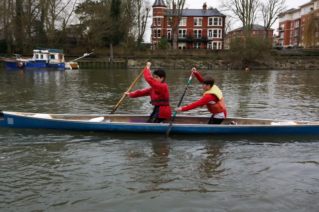 Two kids canoeing wearing yellow buoyancy aids and red clothes