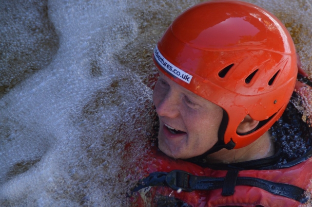 Boy wearing red helmet and smiling while canyoning