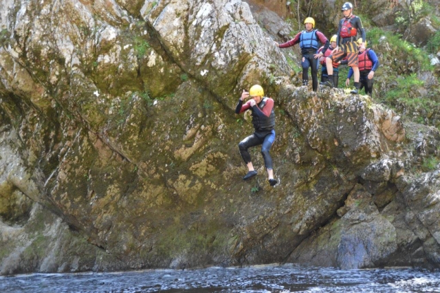 Group of4 people plus instructor wearing safety equipment canyoning