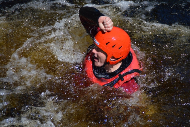 Young boy wearing red safety equipment smiling while canyoning