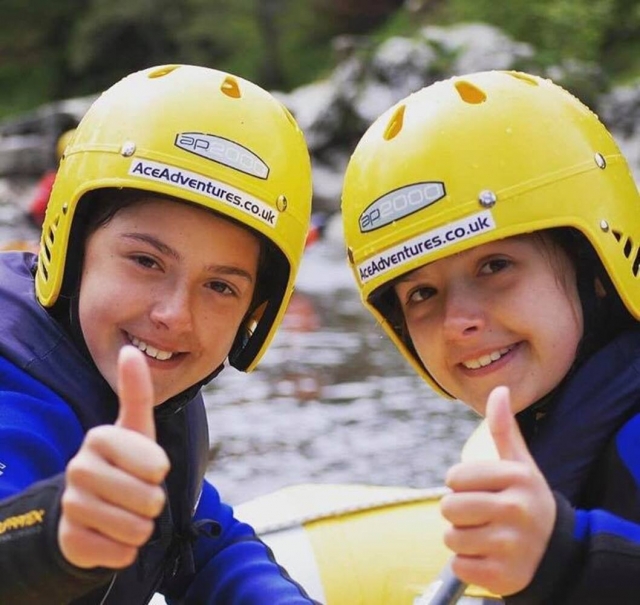  crianças usando capacetes amarelos e auxílios azuis de flutuabilidade se divertindo com o canyoning conosco 