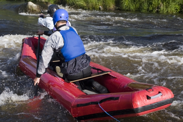 Young boy wearing blue equipment canoeing on the river