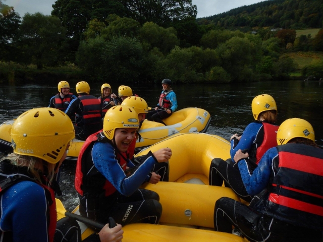 Young people of 17 wearing yellow helmets and red buoyancy aids canoeing