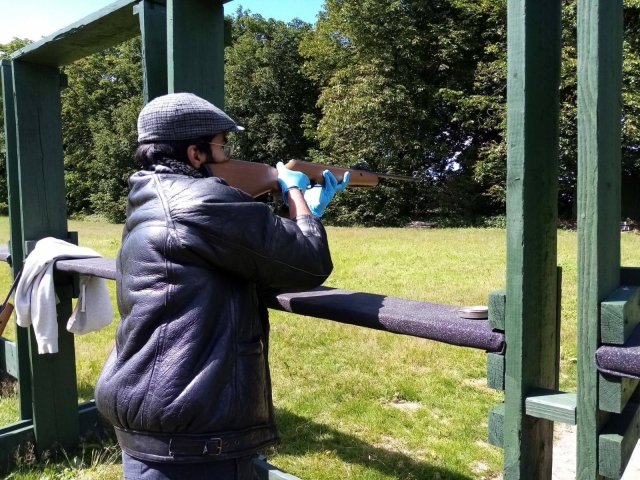 Man in leather jacket and cap rifle shooting