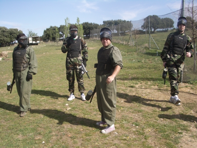  Vier Männer bereiten sich in Tarnanzügen auf das Paintballspiel vor 