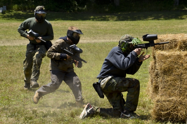 Gruppe in Tarnanzügen spielt Paintball 