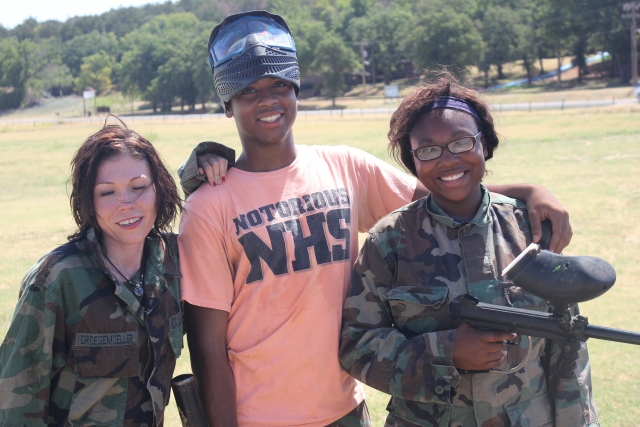 Three friends, two of them wearing camouflage suits, playing paintball