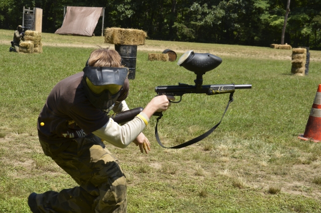 Boy wearing black t-shirt and camouflage pants playing paintball