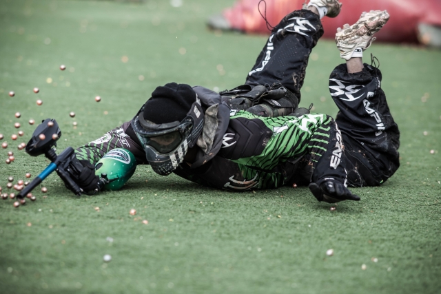  Giocatore di paintball che indossa un abito nero sul pavimento dopo essere stato colpito da un proiettile