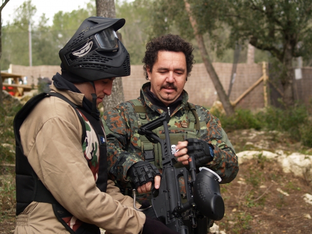  Due amici in tuta mimetica e maschera nera si preparano per giocare a paintball 