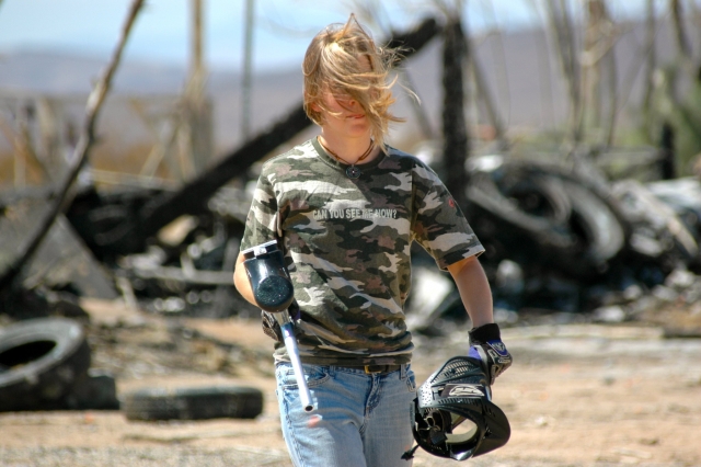 Fille portant un t-shirt et un jean camouflage enlevant le masque après avoir joué au paintball 