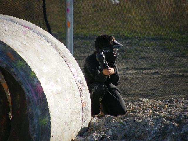 Jogador de paintball usando máscara preta pronta para atirar 
