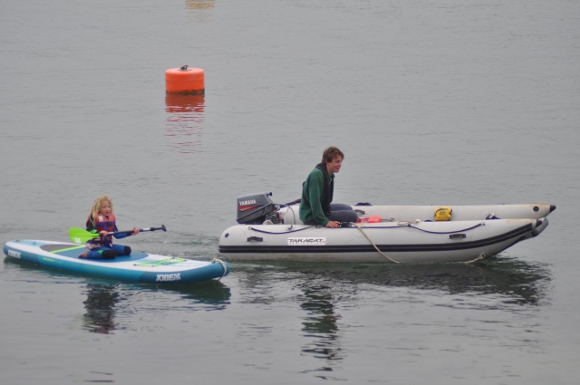 Woman kayaking while a little girl is paddleboarding