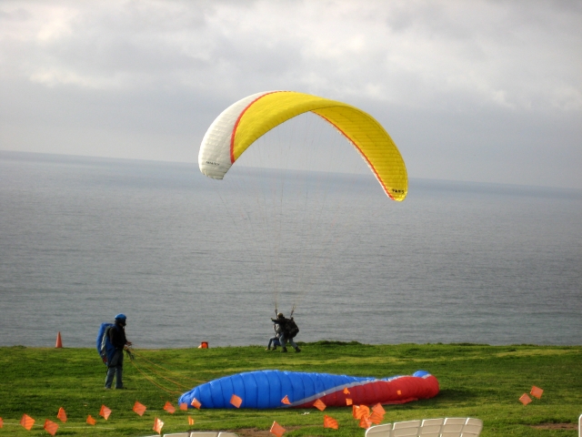 People about to fly thanks to a yellow flying paraglider