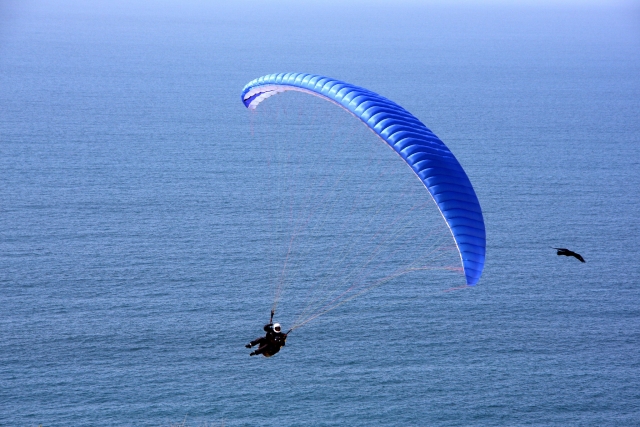 Flying over the sea on a blue flying paraglider