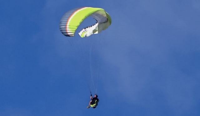 Person flying on blue, white and green flying paraglider