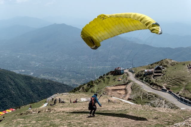 Man in blue sweater getting ready to paragliding on yellow flying paraglider