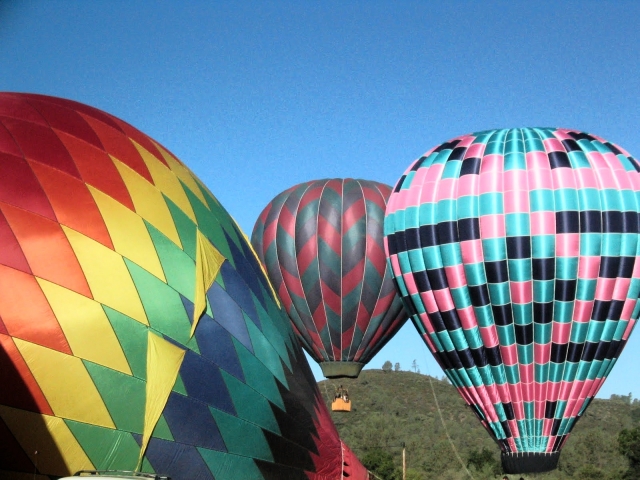 Three colourful balloons flying over the forest