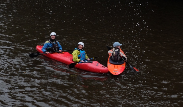 Couple portant des aides à la flottabilité bleues et un casque sur un kayak rouge faisant notre kayak tandem 