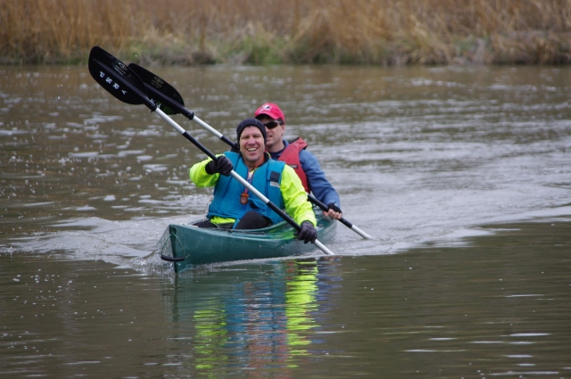  Couple souriant, portant des aides à la flottabilité bleues sur un kayak tandem vert 